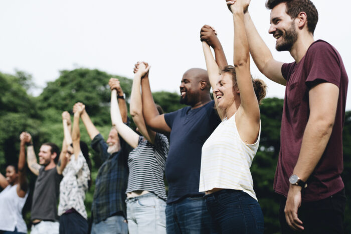 Happy diverse people holding hands in the park