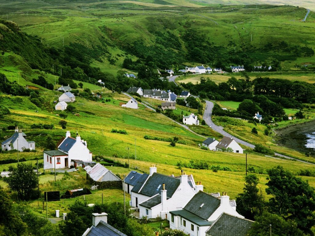 A village on a hillside. Several white houses with grey roofs.