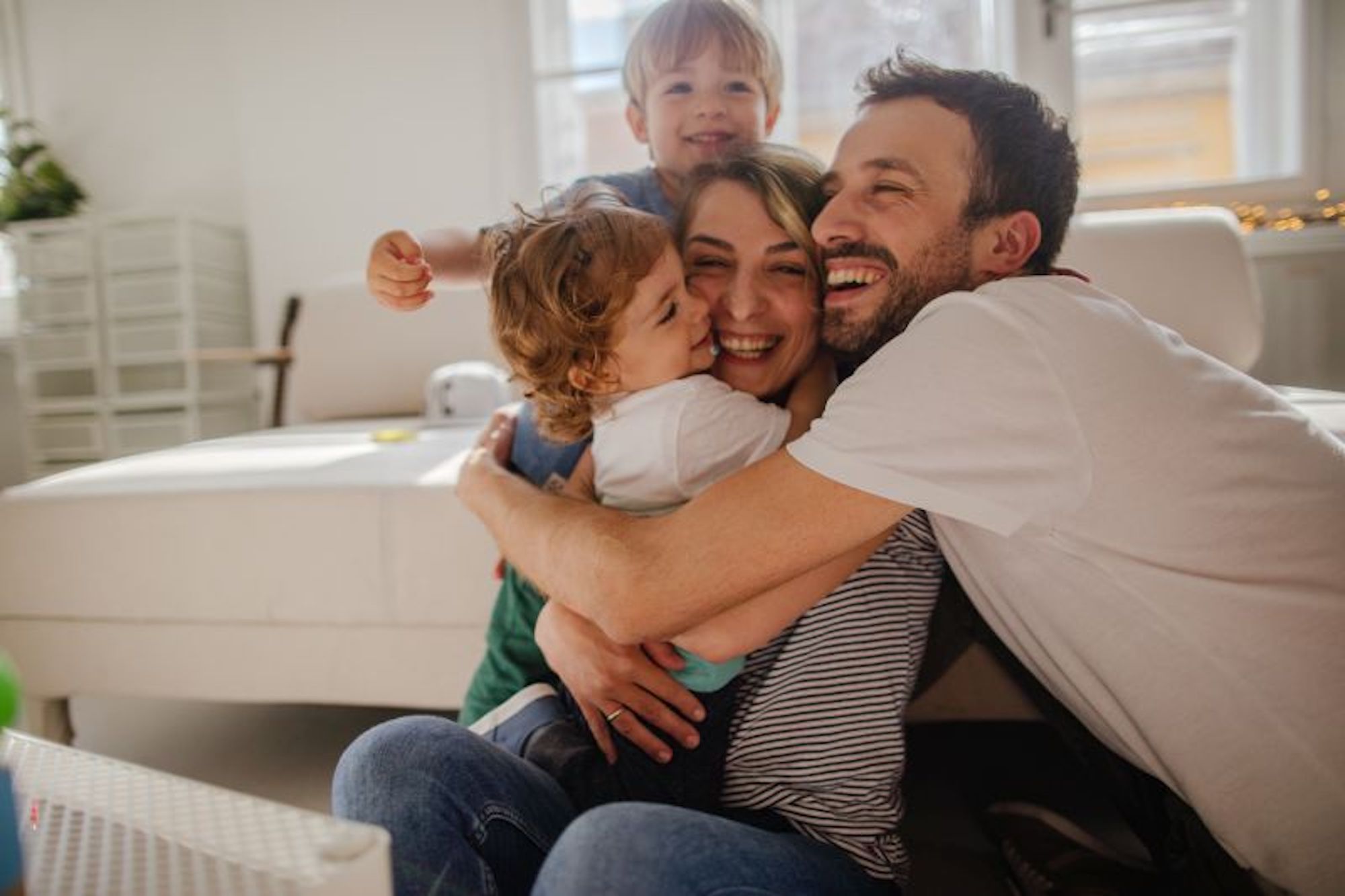 A mum and a dad happily cuddle their two young children.