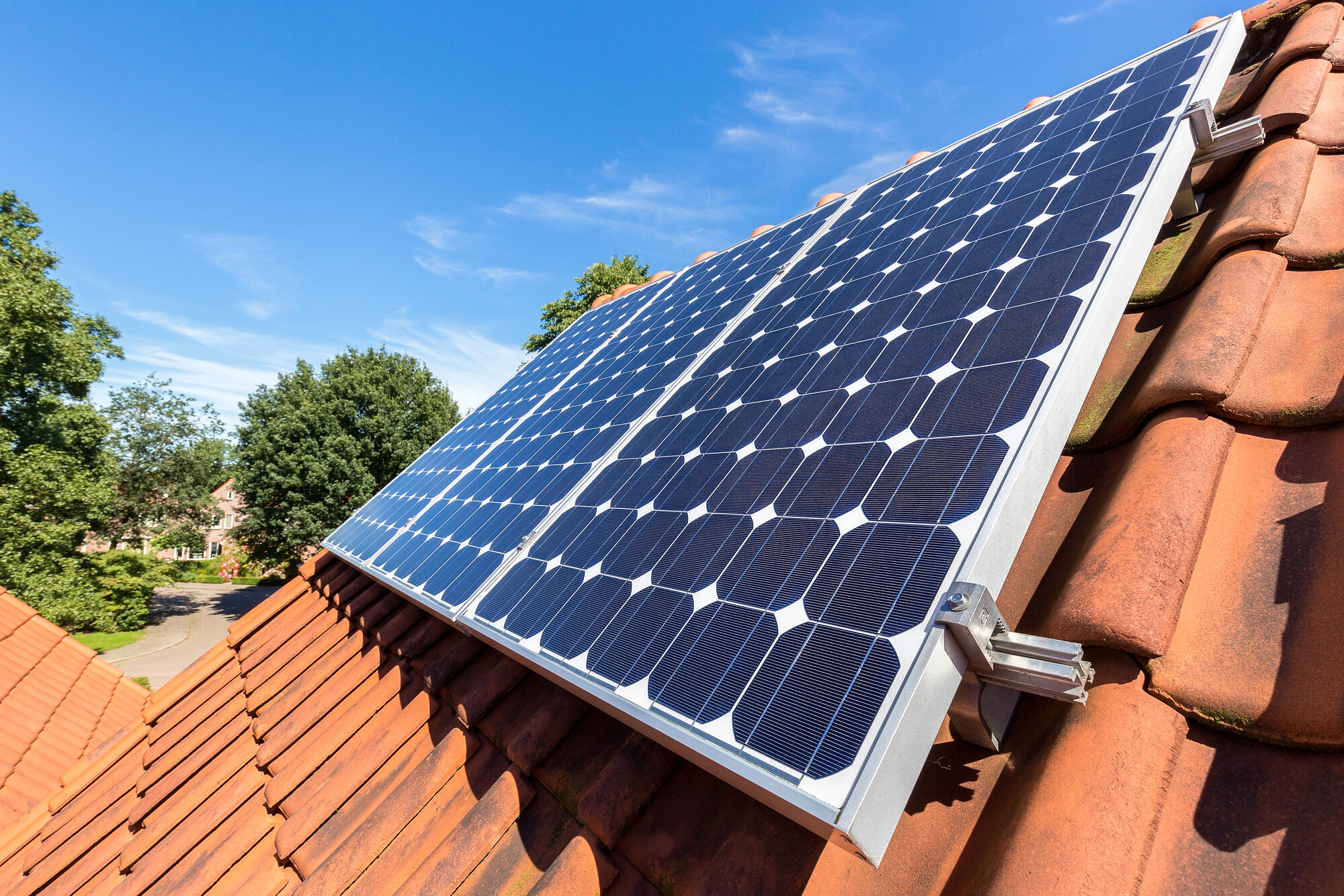 Row of blue solar panels on an orange roof.