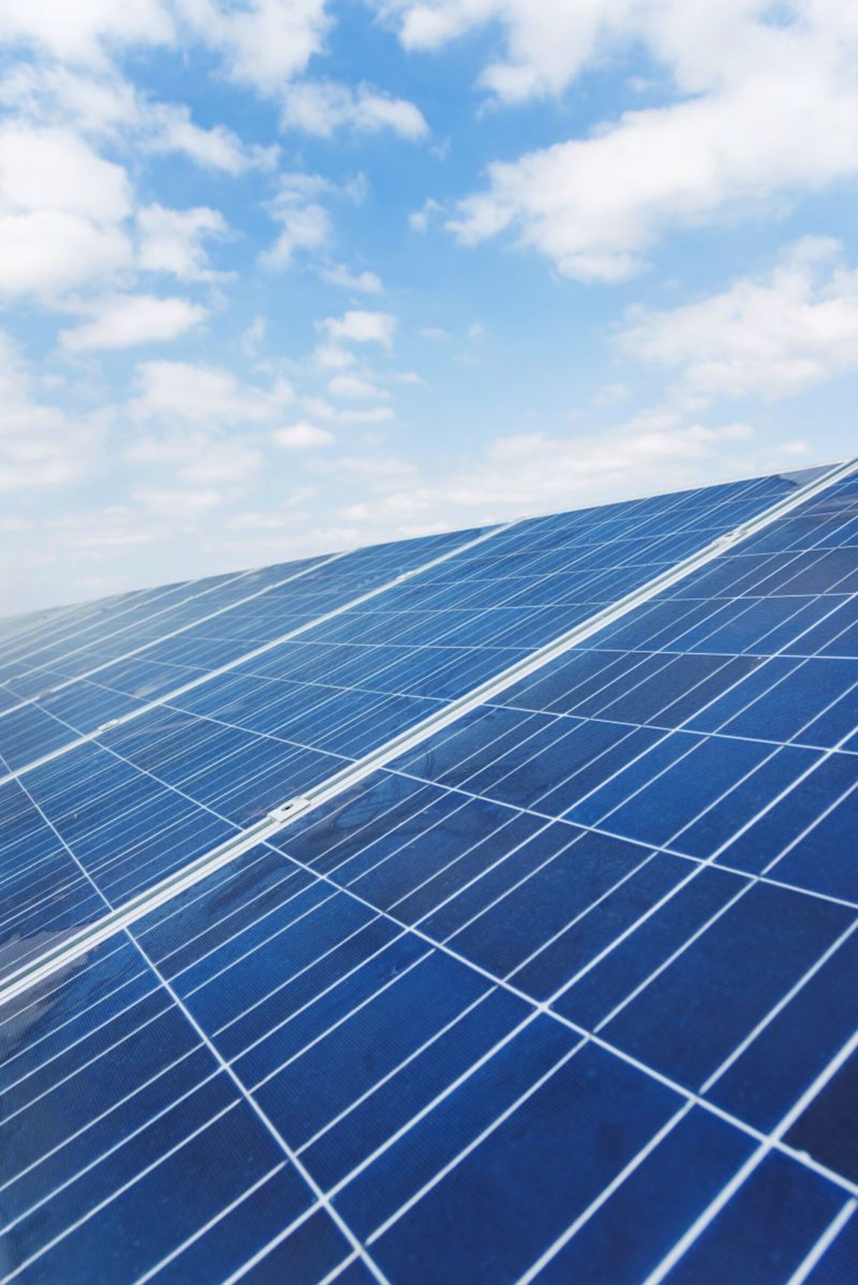 close up of solar panels against blue sky and clouds