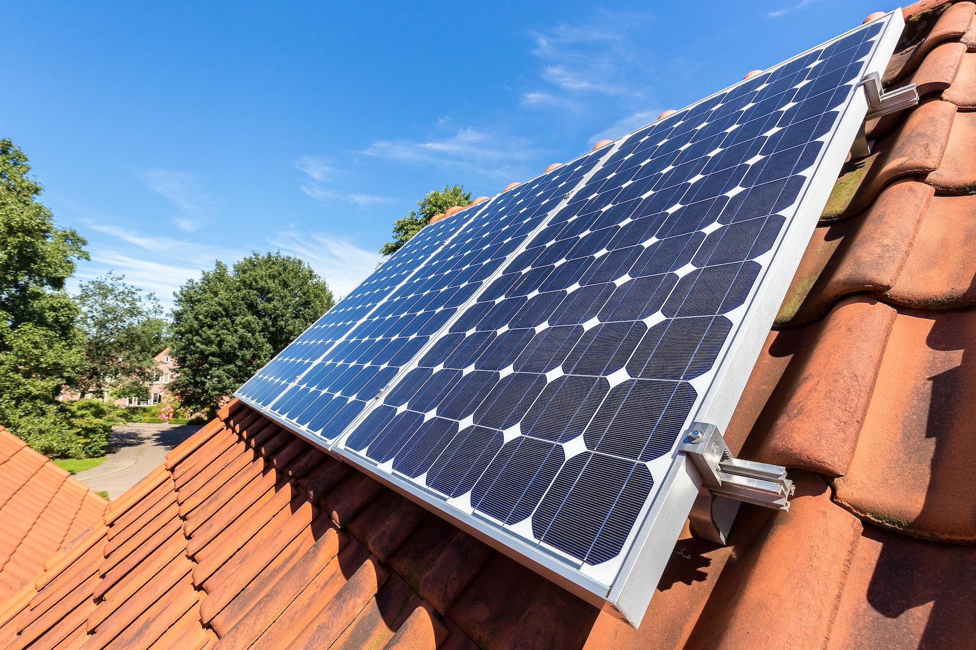 Row of blue solar panels on orange roof.