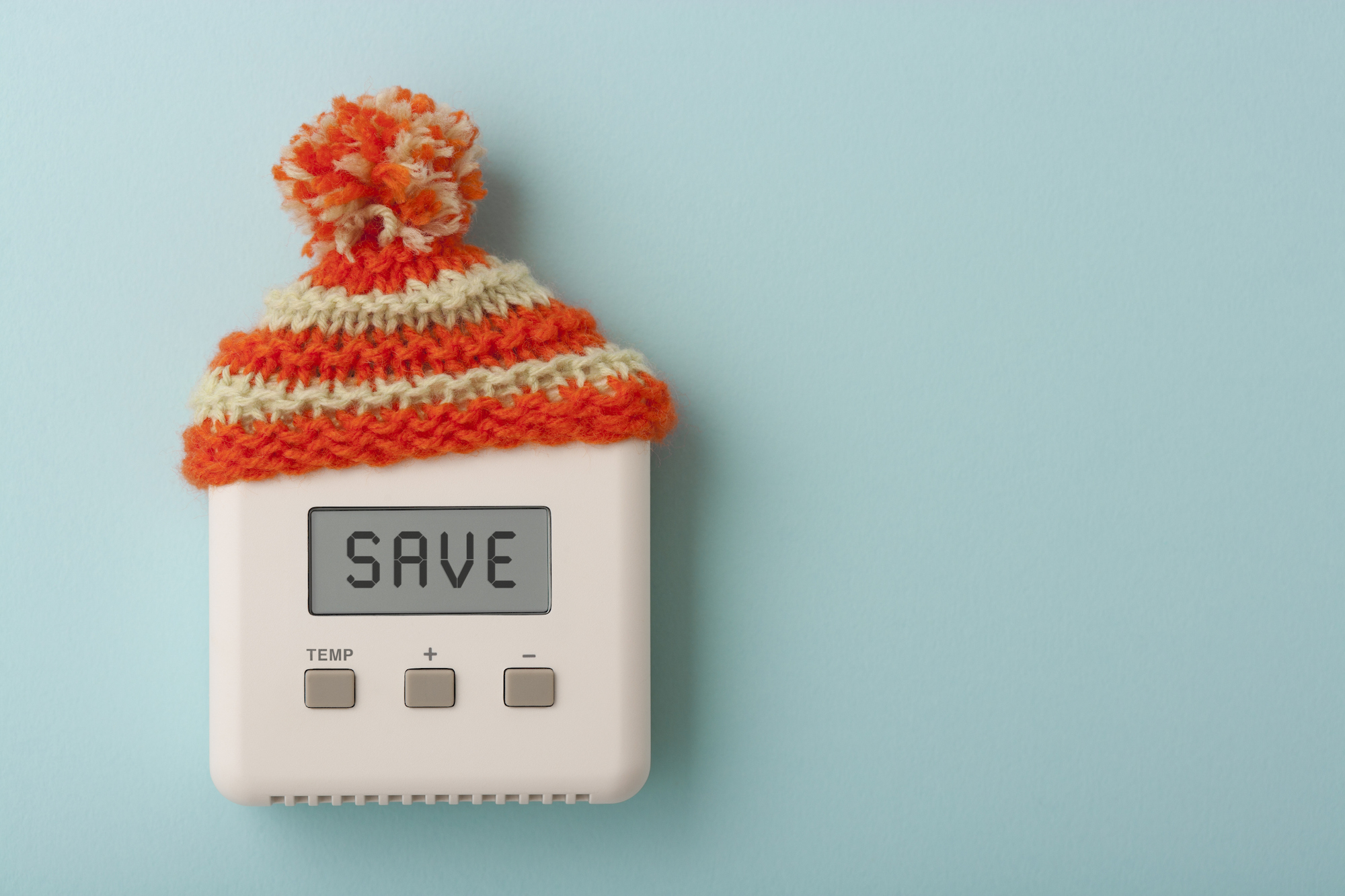 A thermostat with a wooly hat on. The screen on the thermostat reads "SAVE"