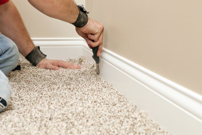 Person using a tool to lift the carpet before installing underfloor insulation