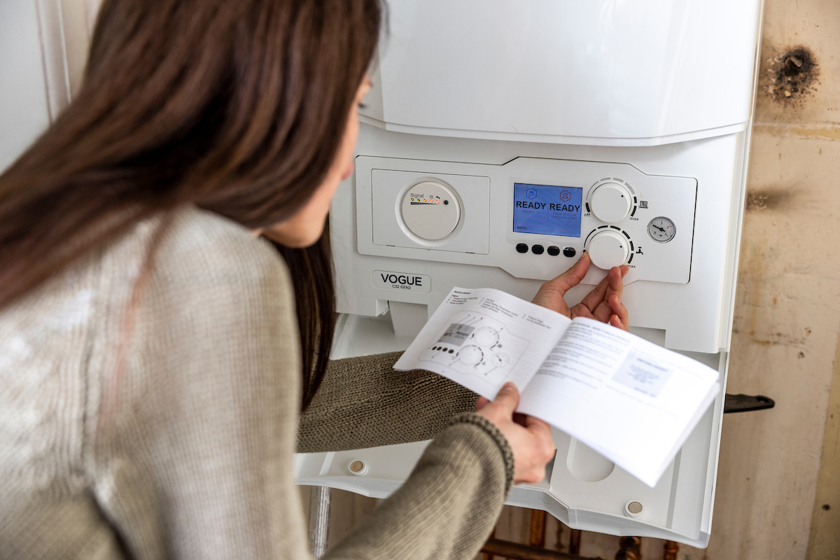 A woman checks the settings on her boiler.
