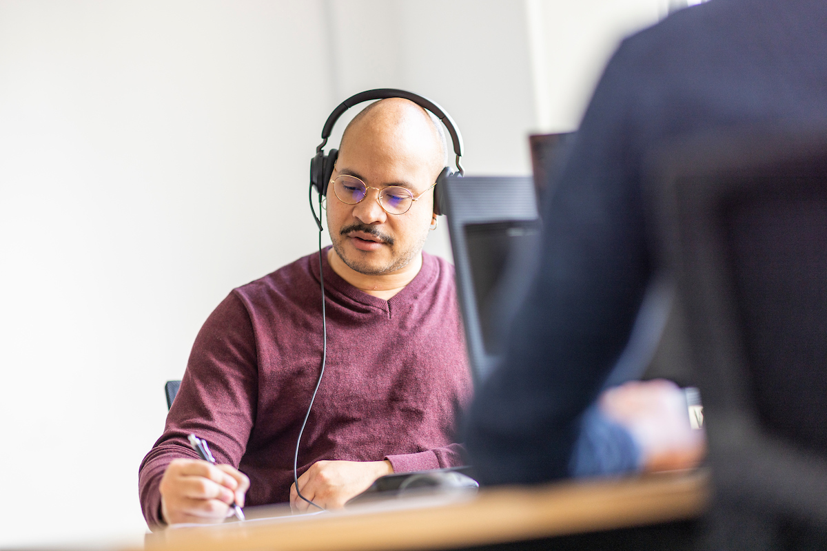 A man wears a headset to talk to someone on the phone.