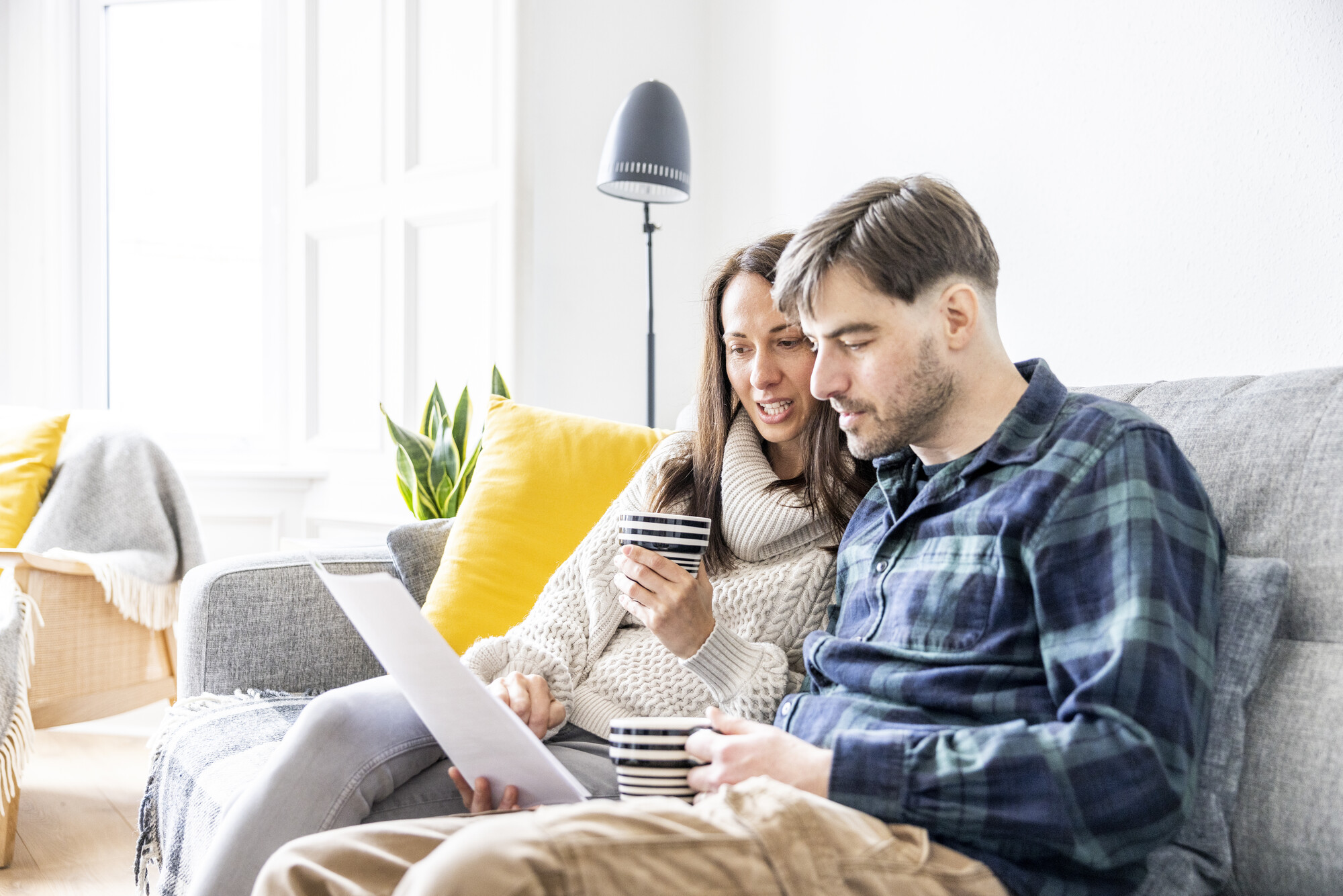 A man and woman drink tea and look at their latest energy bill.