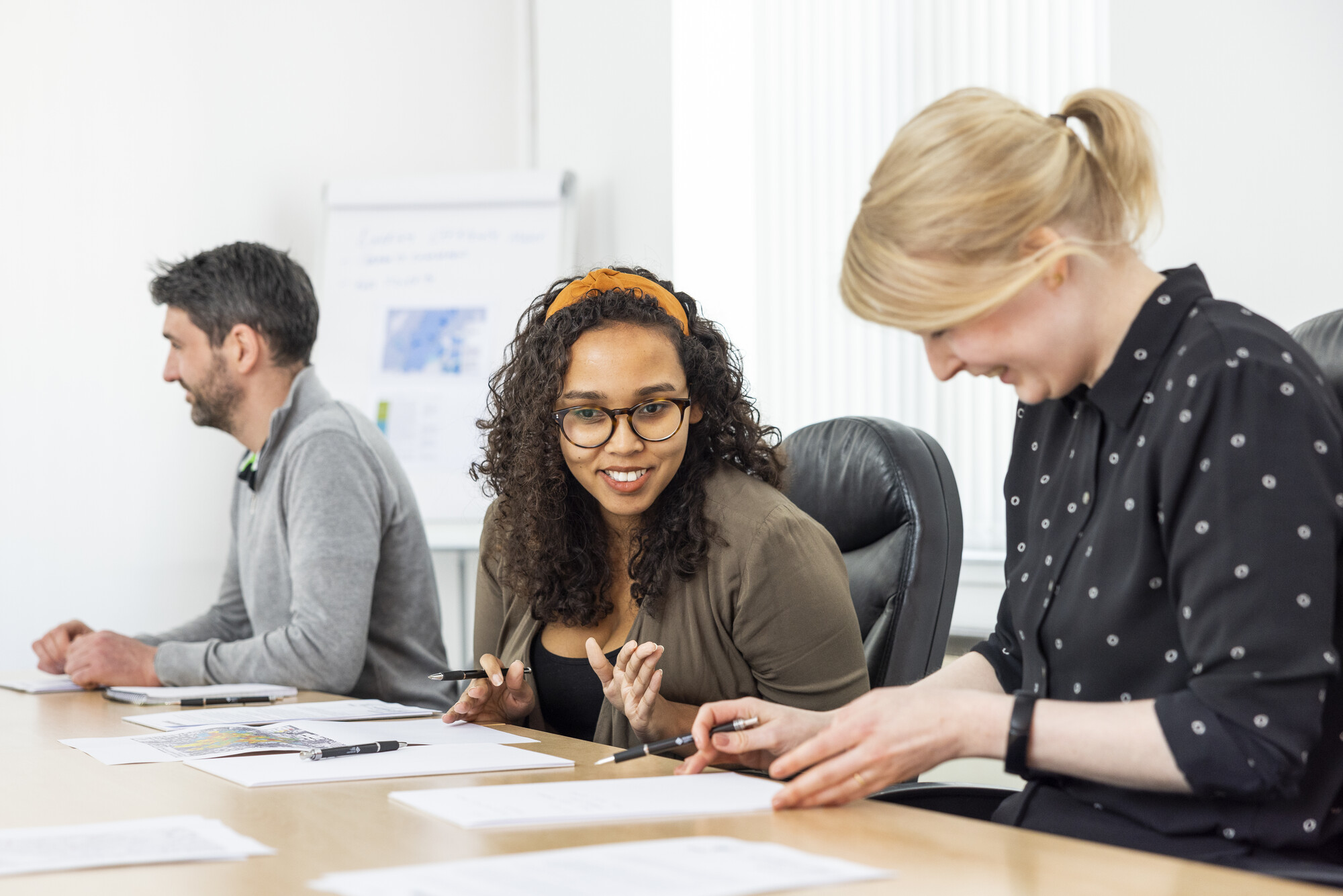 Colleagues discuss work at a large table.