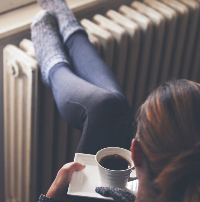 A woman warming her feet on a radiator