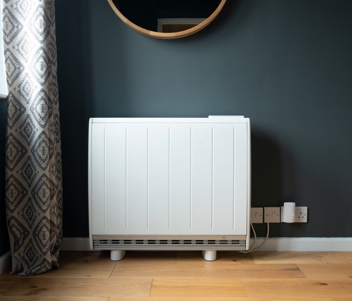 A white storage heater against a green wall