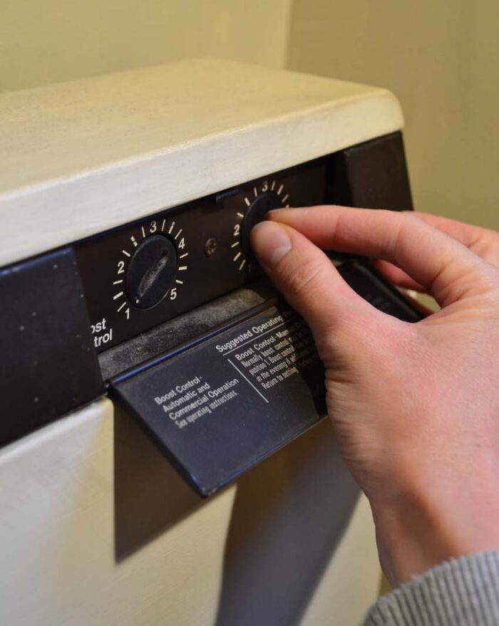 Controls on a storage heater. There are two dials. Someone is turning the second dial