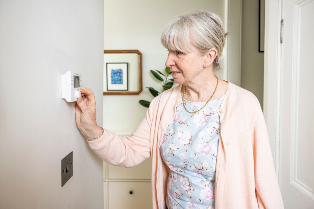 Woman in hallway adjusting thermostat