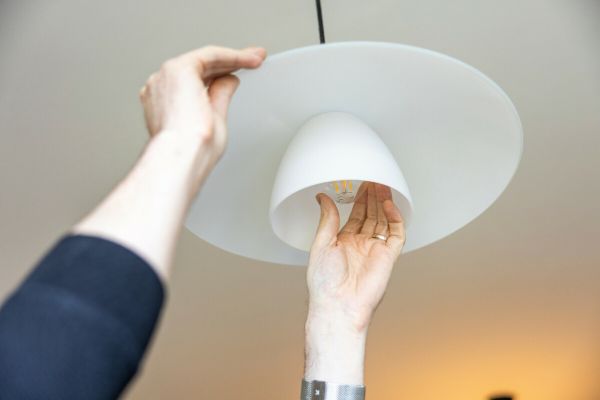 Close up of hands unscrewing a lightbulb from an overhead light