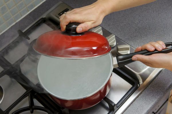 Close up of hands placing a lid on a red pan