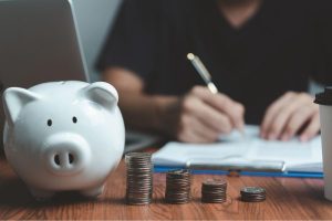 A piggy bank and four stacks of coins on a table
