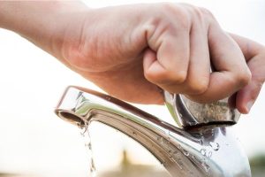 A hand turning off a water tap