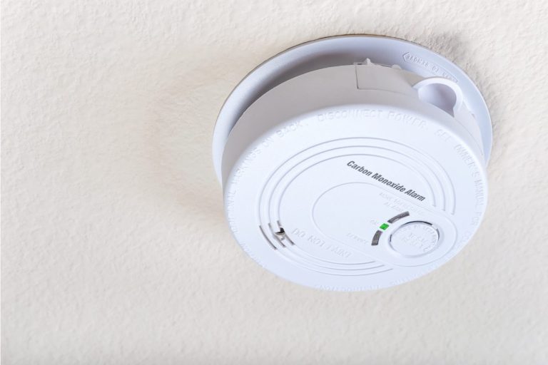 A white, circular carbon monoxide alarm on a ceiling