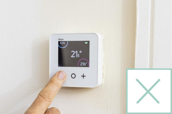 Finger adjusting the temperature on a thermostat, with a cross in the corner