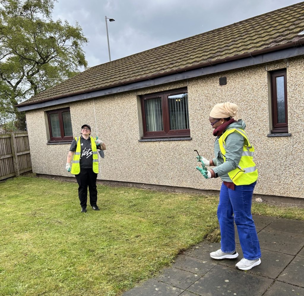 Two volunteers in high viz litter picking on the grass and path