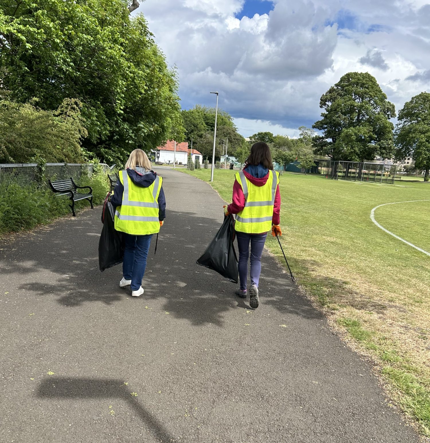 Two people in hi-viz on a litter pick through a park