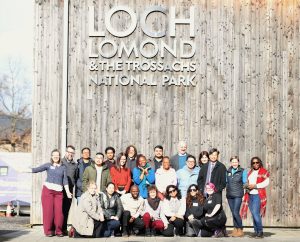 Group of people underneath a sign that reads Loch Lomond and the Trossachs National Park