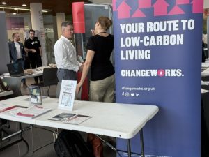 Two people behind a stall with a banner that reads "your route to low carbon living"